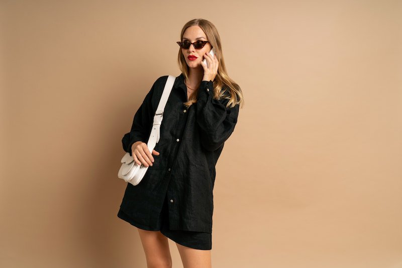 trendy-studio-portrait-of-stylish-woman-speaking-by-her-smartphone-influencer-job-wearing-black-linen-suit (1)
